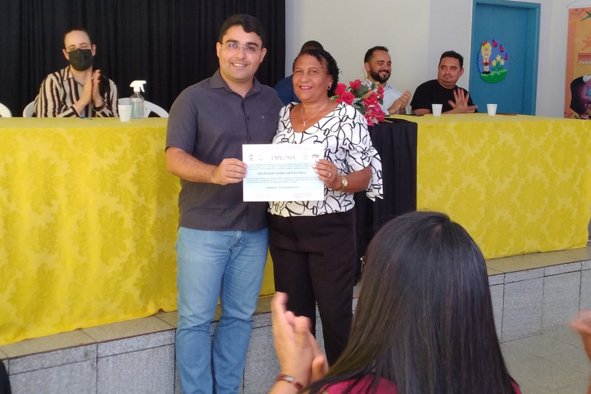 Na - imagem - a - Conselheira - Reginalda- Moura - recebendo - seu – diploma – das - mãos - do – Secretário – de - Administração - da – Prefeitura - Amandino - Júnior