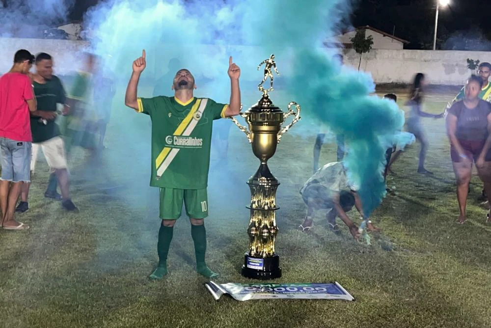 Atleta-de-Curralinhos-ao-lado-do-troféu-gigantesco-de-campeão-levantado-aos-mão-para-o-céu-agradecendo-a-Deus-pela-conquista