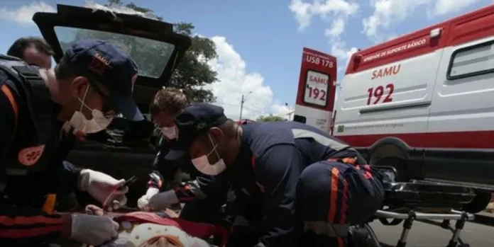 Na-foto-aprecem-ambulância-e-socorrista-do-SAMU-prestando-os-primeiro-os-socorros-a-vítima-de-acidente-de-trânsito